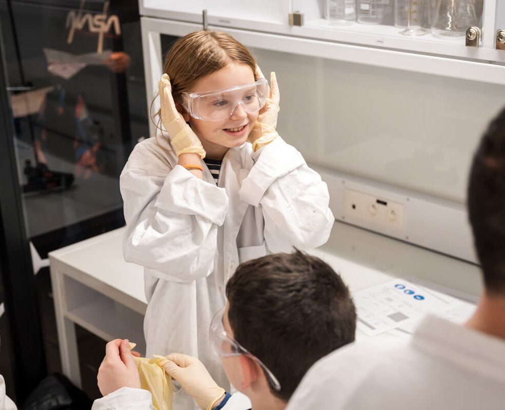 Famille dans un atelier labo avec petite fille qui bouche ses oreilles