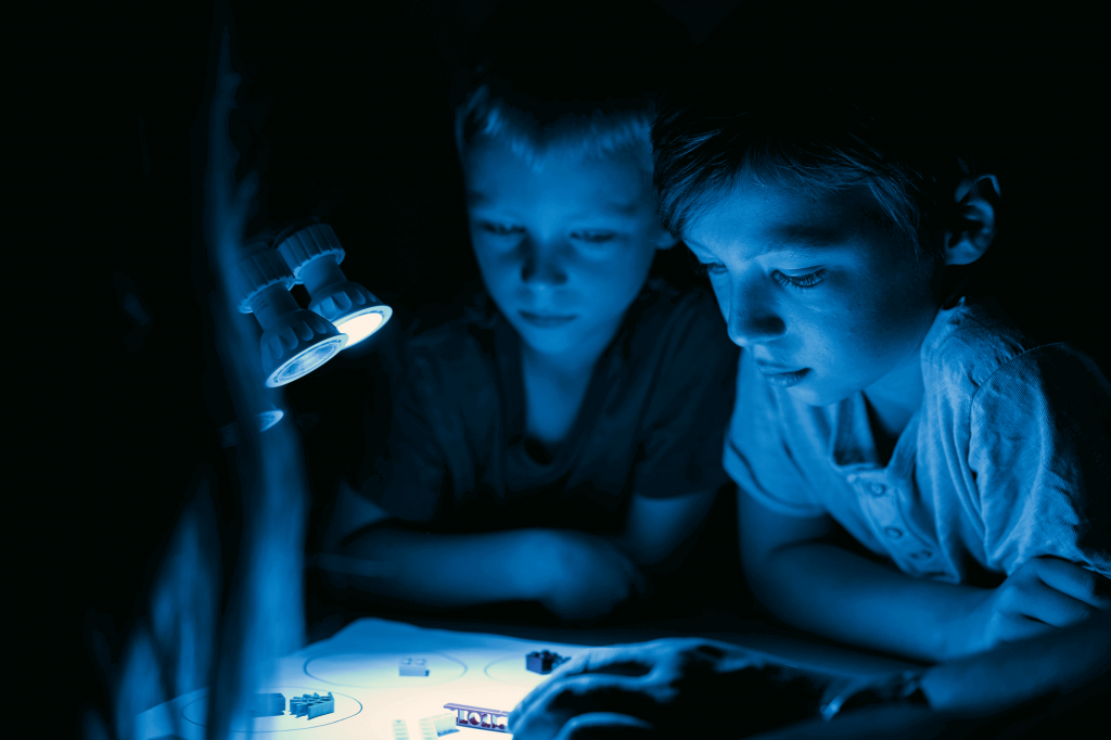 Deux enfants dans la pénombre font des jeux de lumière